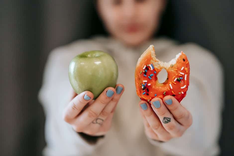 A person holding a green apple in one hand and a partially eaten sprinkle-covered donut in the other, symbolizing a choice between healthy and indulgent options.