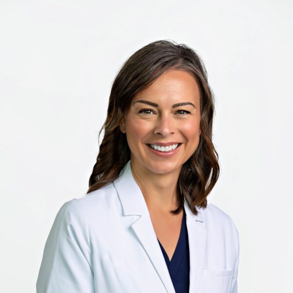 A woman with medium-length brown hair, wearing a purple top and smiling, standing in front of a white background.